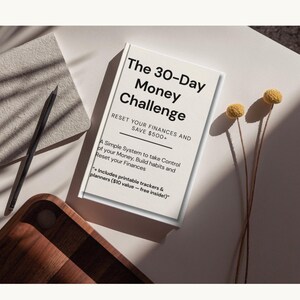 Op de afbeelding: Een wit boek met de titel "The 30-Day Money Challenge" met de tekst "Reset Your Finances and Save €500+". Het boek ligt op een wit oppervlak met een potlood, een houten dienblad en gedroogde gele bloemen. De ondertitel van het boek is "A Simple System to take Control of your Money, Build habits and Reset your Finances."