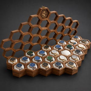 May include: A wooden watch display case with a honeycomb structure featuring multiple hexagonal compartments. Each compartment holds a wristwatch on a white cushion. The top lid is open, displaying the letters SC with a crown icon above them.
