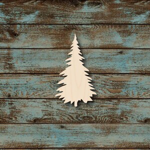 May include: A wooden cutout of a pine tree, unpainted, with a detailed silhouette. The tree is set against a rustic background of weathered, blue-toned wooden planks. The tree's shape is clearly defined, showcasing its branches and overall form.