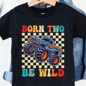 May include: Black t-shirt with a colorful graphic of a monster truck and the text "BORN TWO BE WILD". The monster truck is blue and orange, set against a checkered background.