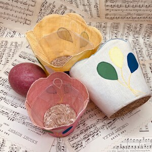 May include: Three fabric baskets with different patterns and colors. The baskets are made of a soft, textured fabric and have a round shape. The baskets are perfect for storing small items or for use as decorative accents.