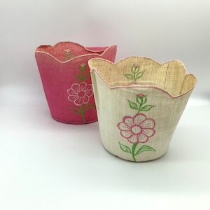 May include: Two fabric flower pot covers. One is pink with a white flower design and the other is white with a pink flower design.
