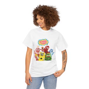 May include: White t-shirt featuring the text "Yo Gabba Gabba!" in a blue and yellow burst. The shirt displays a colorful graphic of the show's characters, including a yellow robot, red creature, and blue monster. The shirt is made of a soft material.