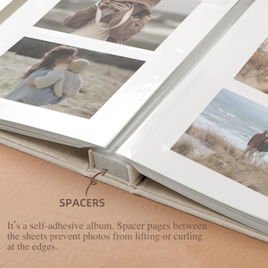 May include: Open photo album with white pages and photos. The album is open, revealing several pictures with white borders. The text "SPACERS" is visible, along with a description about the album's self-adhesive design.