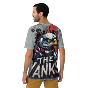 May include: A light gray t-shirt featuring a graphic of an American bald eagle with a red, white, and blue scarf. The text "THE YANKS" is displayed in bold, white letters. The shirt has a crew neck and short sleeves.