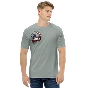 May include: A light gray t-shirt featuring a graphic of an eagle with the American flag and the word "Yanks" in red dripping letters. The shirt has short sleeves and a crew neck.