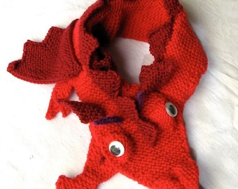 May include: Red knitted dragon scarf with purple accents and googly eyes.