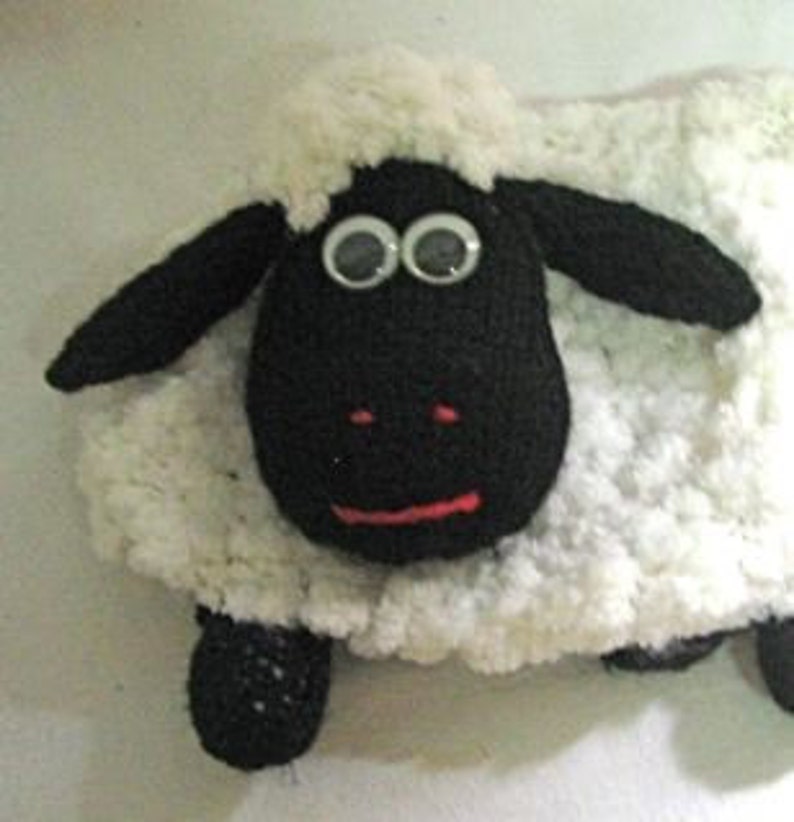 May include: A black and white crocheted sheep plush toy with large googly eyes. The sheep has a white fluffy body and black face, ears, and legs.