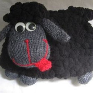 May include: A black knitted plush toy sheep with large googly eyes and a red tongue. The sheep has a fluffy texture and is a handmade craft.