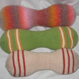 May include: Three knitted, colorful,  pillow-shaped dog toys. The top toy is pink, orange, and gray. The middle toy is green with white and orange stripes. The bottom toy is beige with red and white stripes.