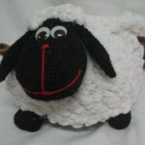 May include: White crocheted teapot cozy shaped like a sheep with a black face, red nose, and black legs.
