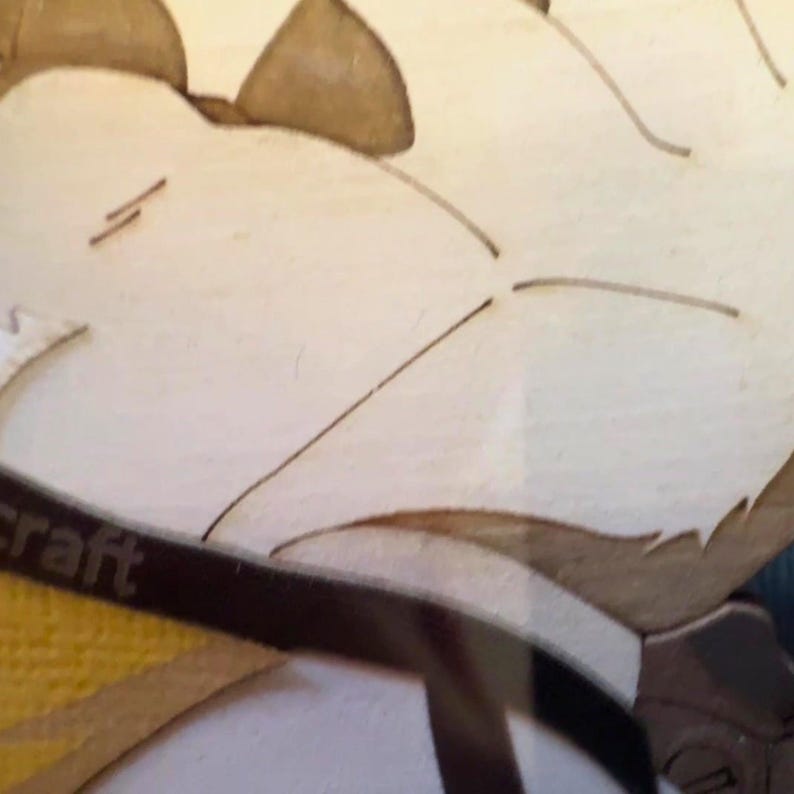 Puede incluir: Un recorte de madera de color claro con l&iacute;neas grabadas con l&aacute;ser que forman una silueta animal estilizada. Una banda marr&oacute;n oscuro con el texto parcial craft es visible en la secci&oacute;n inferior, ocultando parcialmente la superficie texturizada amarilla.