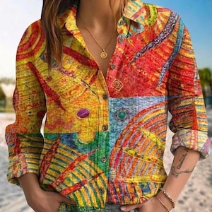 Pode incluir: Uma camisa abotoada com um padrão abstrato vibrante em amarelo, vermelho, azul e verde. A camisa de manga comprida tem gola e é combinada com jeans cinza. O design colorido apresenta formas geométricas e pinceladas artísticas.