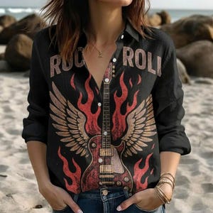 Pode incluir: Camisa preta com botões com um desenho de guitarra. A guitarra tem asas e é rodeada por chamas vermelhas. As palavras "ROCK ROLL" são impressas acima da guitarra em castanho. Usada com calças de ganga azuis.