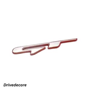 May include: A chrome car emblem with a red trim. The emblem features a distinctive shape and the text "Drivedecore" at the bottom. This is likely a decorative or branding element for a vehicle.
