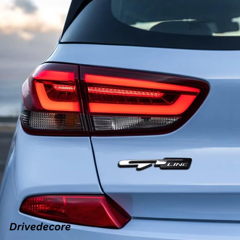 May include: Rear view of a light blue car with a red tail light and a black and silver "GT LINE" emblem. The text "Drivedecore" is visible at the bottom of the image.