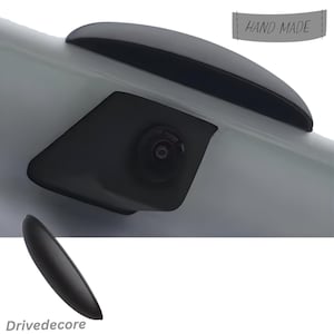 May include: A close-up of a car part with a black camera and a black trim. The text "HAND MADE" is on a gray banner. The logo "Drivedecore" is at the bottom.