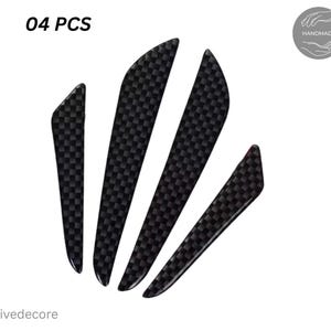 Puede incluir: Cuatro protectores negros para manijas de puertas de coche con textura de fibra de carbono. Los protectores tienen varias formas y tamaños. El texto "04 PCS" está en la esquina superior izquierda. La palabra "Handmade" está en un círculo en la esquina superior derecha.