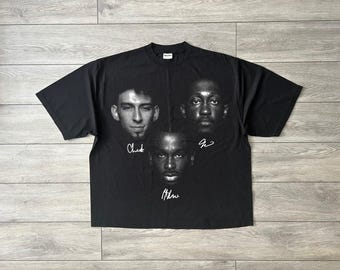 May include: Black t-shirt featuring three grayscale portraits with signatures below each. The signatures read "Chad", "J", and "Athw". The shirt is made of a soft material and has a crew neck.