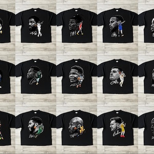 May include: Black t-shirts featuring portraits of basketball players with their signatures. Each shirt displays a different player, with various action poses and team colors. The shirts are arranged in a grid pattern.