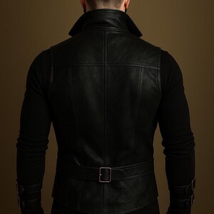 May include: Black leather vest with a notched collar, belt, and buckle details. The vest has a tailored fit and is worn over a black long-sleeved shirt. The back of the vest features vertical and horizontal stitching.