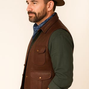 May include: A brown leather vest with two front pockets and a button closure. The vest is worn over a dark green long-sleeved shirt and paired with a brown fedora hat and a blue bandana.