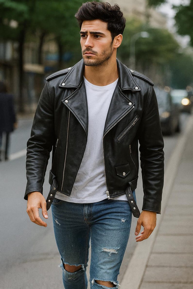 May include: A black leather motorcycle jacket with silver zippers and snaps. The jacket is worn over a white t-shirt and paired with blue jeans. The model is walking on a city street.
