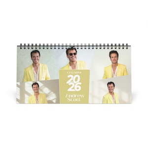May include: A spiral-bound desk calendar featuring multiple images of a person in a yellow blazer. The calendar has a light green background with the text "CALENDAR 2026 Andrew Scott".