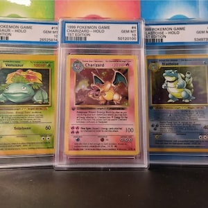 Puede incluir: Tres cartas de juego Pokémon de 1999 en fundas protectoras. Las cartas presentan a Venusaur, Charizard y Blastoise. Cada carta está etiquetada como 1ª edición y calificada GEM MT 10. La carta de Charizard tiene un fondo rojo y naranja.