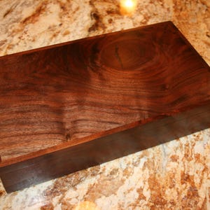 May include: A rectangular wooden box with a dark brown walnut finish. The wood grain is visible and has a natural, rustic look.