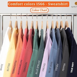 May include: A color chart of Comfort Colors 1566 sweatshirts in various hues, including white, butter, terracotta, watermelon, crimson, light green, blue spruce, orchid, blue jean, denim, pepper, and true navy. The text "Comfort colors 1566 - Sweatshirt" is displayed.