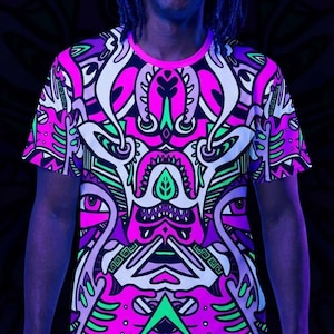 Könnte beinhalten: Ein kurzärmeliges T-Shirt mit Rundhalsausschnitt und einem lebendigen, symmetrischen Grafikdruck in Neonpink, leuchtendem Grün, Violett und Weiß. Das komplexe Muster zeigt stilisierte organische Formen, scharfe geometrische Linien und abstrakte Augenmotive.