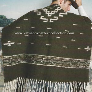May include: Dark green poncho with white geometric patterns and fringe. The poncho has a textured appearance and features a repeating design along the bottom edge. The website address "www.katnaboxpatterncollection.com" is visible on the poncho.