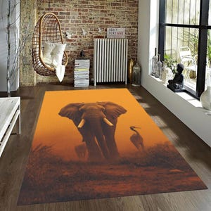 May include: Rectangular area rug featuring an elephant and a bird in a warm, orange-toned landscape. The rug's design includes a large elephant with visible tusks and a bird silhouette, creating a nature-inspired theme for home decor.