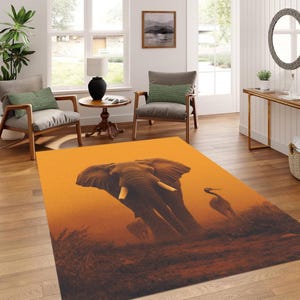 May include: An orange area rug featuring a detailed illustration of an elephant and a bird in a savanna landscape. The rug has a warm color palette with shades of orange, brown, and tan, creating a natural and inviting aesthetic.