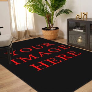May include: A black rectangular rug with the text "YOUR IMAGE HERE" in red. The rug is in a room with a potted plant, a side table, and a chair.