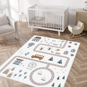 May include: A white play rug with a road map design featuring a Ferris wheel, bus, houses, trees, and a hot air balloon. The rug is designed for a nursery or playroom, with a neutral color palette.
