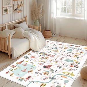 May include: A white play mat with a colorful town and road design. The mat features illustrations of houses, cars, boats, and a lake. The mat is rectangular and placed on a wooden floor in a bedroom setting.