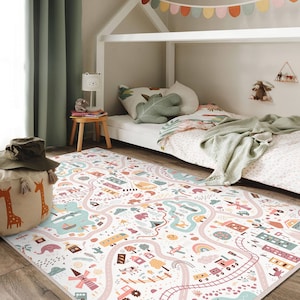May include: A colorful children's play mat with a road map design. The mat features roads, buildings, vehicles, and other playful illustrations in pastel colors. The mat is rectangular and placed on a wooden floor.