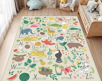 Op de afbeelding: Een beige kinderkleed met een alfabetontwerp, met illustraties van dieren en fruit. Het kleed bevat een blauwe olifant, een roze flamingo, een gele giraffe en een groene krokodil. Het kleed heeft ook de woorden "Watermelon" en "Exotic Mix".