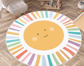 May include: A round area rug with a smiling sun design. The sun is yellow with a white border and colorful rays in shades of pink, orange, yellow, green, and blue. The rug is designed for a child's room.