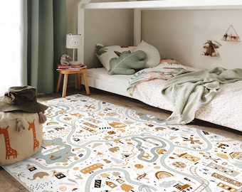 May include: A white children's rug with a road map design featuring roads, vehicles, houses, and trees in shades of brown, tan, and blue. The rug is placed in a child's bedroom, near a bed and a pouf with giraffe illustrations.