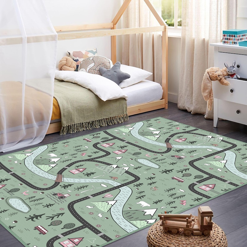 May include: A green play rug with a road map design. The rug features black roads, light blue rivers, pink houses, and white mountains. The rug is in a child's bedroom with a wooden bed frame and a white dresser.