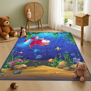 May include: A rectangular children's rug featuring a colourful underwater design. A large red cartoon fish swims above a sandy seabed with various fish, plants, and bubbles. The rug has a blue border and is on a wooden floor.