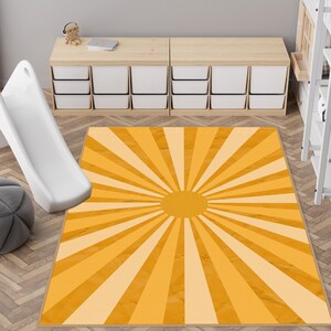 May include: A rectangular rug with a sunburst design in shades of yellow and cream. The rug features a central circular shape with radiating lines, creating a warm aesthetic. The rug is likely made of a soft material, suitable for a living room or bedroom.