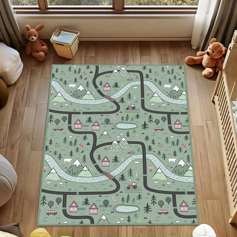 May include: A rectangular play mat with a road map design. The mat features roads, mountains, trees, houses, and a lake in shades of green, gray, and pink. The mat is designed for children's play and learning.