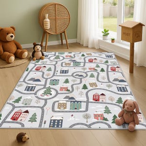 Könnte beinhalten: Eine graue Spielmatte mit einem Stadt- und Straßendesign. Die Matte zeigt bunte Häuser, Bäume, Berge und Straßen. Die Matte ist rechteckig und liegt auf einem Holzboden. Ein brauner Teddybär und ein Stoffhase befinden sich in der Nähe.