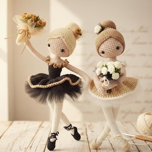 May include: Two handmade crochet ballerina dolls. One doll wears a black tutu with a gold trim and holds a bouquet of yellow flowers. The other doll wears a tan tutu and holds a bouquet of white flowers. Both dolls have ballet shoes.