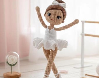 May include: A handcrafted crochet ballerina doll with a white tutu, ballet shoes, and a brown bun. The doll has a sweet expression and is posed with arms raised. The doll is approximately 8 inches tall.