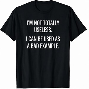 以下が含まれることがあります： 「I'M NOT TOTALLY USELESS. I CAN BE USED AS A BAD EXAMPLE.」という白文字がプリントされた黒いTシャツ。半袖でクルーネックのデザインです。テキストは前面の中央に配置されています。